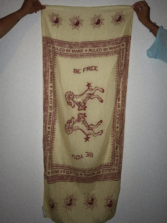 Yellow fabric with red text and symbols, held by two hands against a plain background