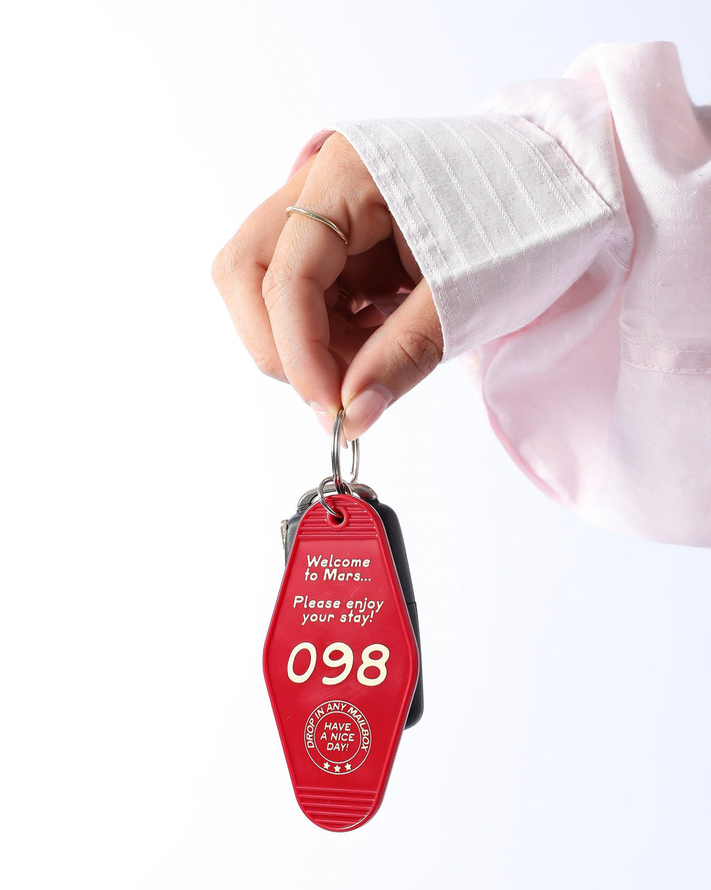Red keychain with text held by a hand on a white background