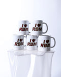 Five white mugs with 'I ❤️ RBM' text on a reflective surface.